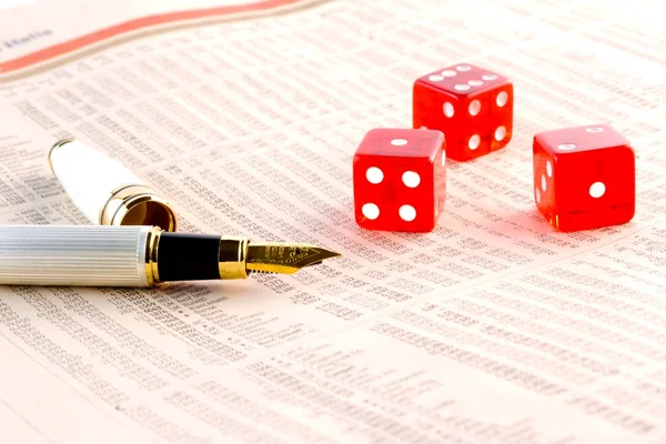 Rode dobbelstenen en een gouden pen op de financiële krant — Stockfoto