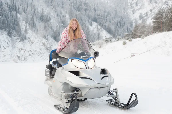 Vrouw een sneeuwscooter rijden Stockafbeelding