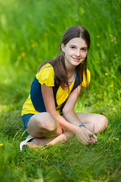 Een meisje, zittend op groen gras — Stockfoto