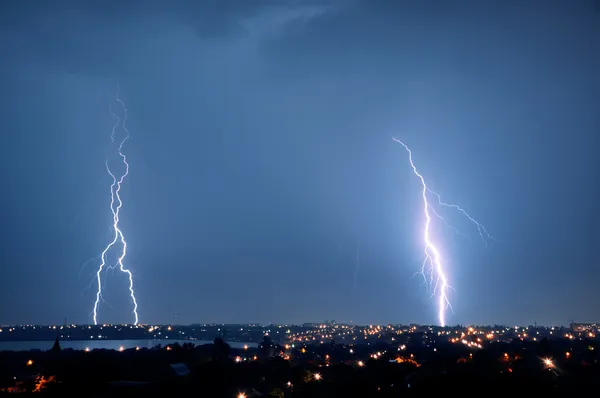 Lightning strike over dark blue sky in night city - Stock Image - Everypixel