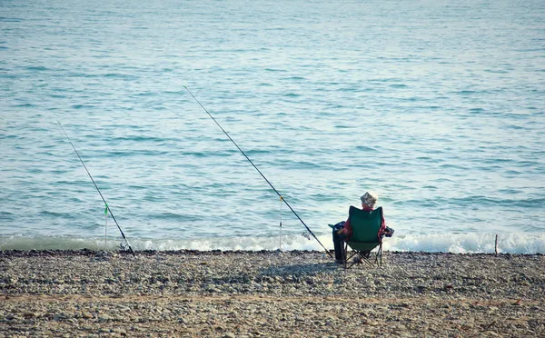 Rybář s rybářský prut rybolov na pozadí moře — Stock fotografie