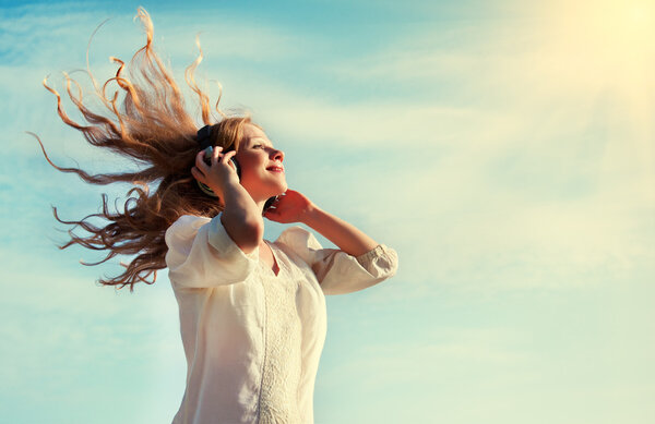 Beautiful girl listening to music on headphones in the sky — Stock Photo, Image