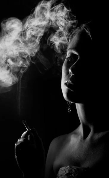 Krásná dívka s cigaretou v temnotách — Stock fotografie