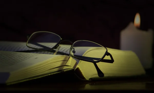 Glasögon, bok och ett ljus — Stockfoto