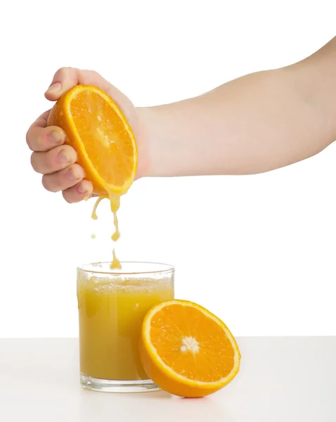 Hand squeezes the juice from the orange into a glass — Stock Photo, Image