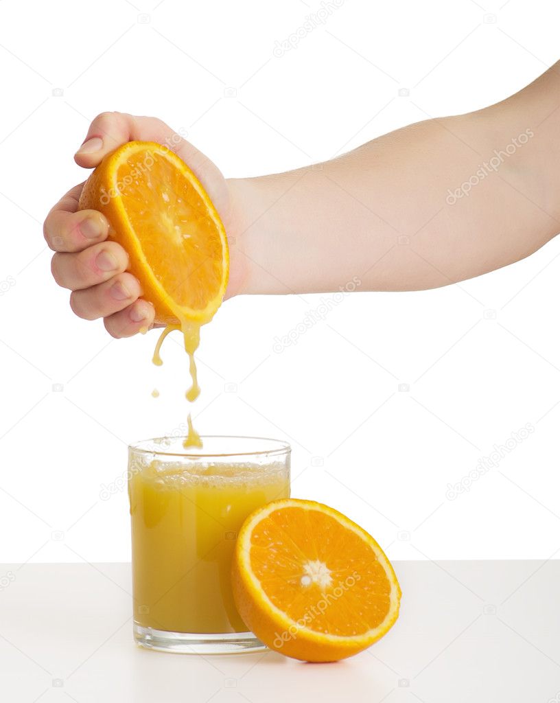 Hand squeezes the juice from the orange into a glass
