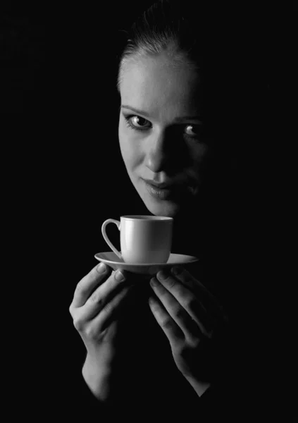 Vacker flicka med en kopp kaffe på en svart bakgrund — Stockfoto