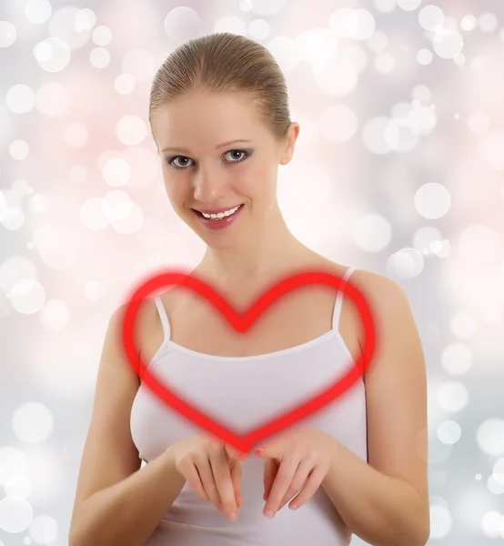 Beautiful young woman draws a big red heart — Stock Photo, Image