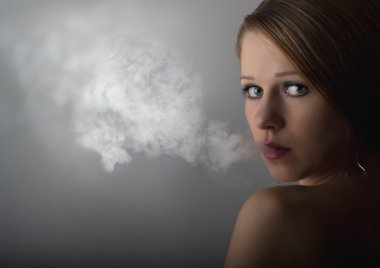 Beautiful young woman with cigarette smoke on a dark gray backgr clipart