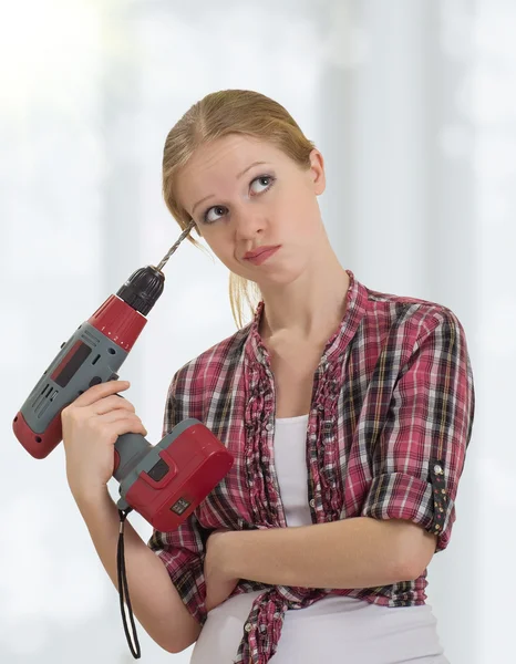 Funny beautiful girl with a drill drills head — Stock Photo, Image