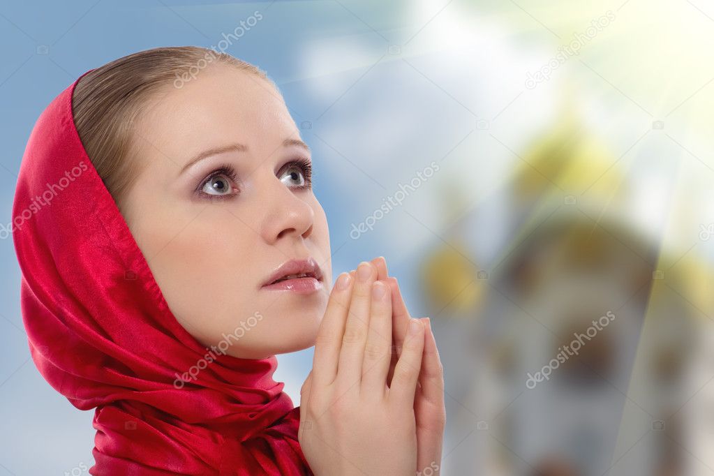 Beautiful young woman in a scarf prays to God