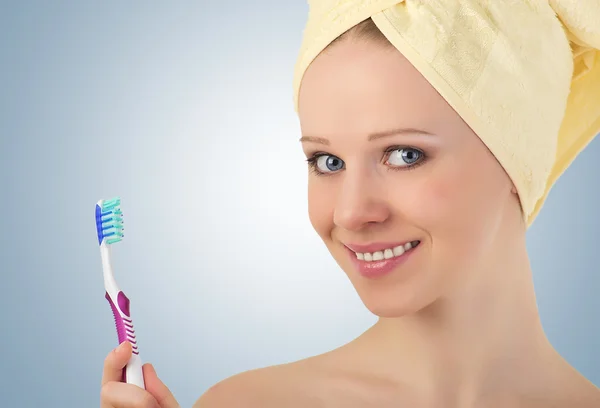 Jovem mulher saudável em uma toalha amarela com uma escova de dentes em seu h — Fotografia de Stock