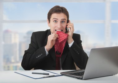 Frightened frustrated business man talking on the phone clipart