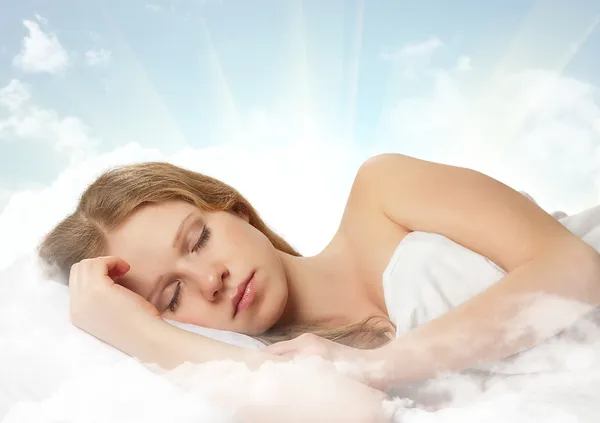 Gökte tek bir bulut üzerinde uyuyan güzel genç kadın — Stok fotoğraf