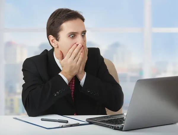 Surprised frightened businessman looking at a laptop, his han — Stock Photo, Image
