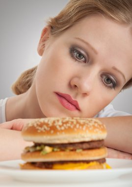 güzel kız, diyet, hamburger seyir için üzgün oturur
