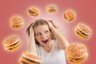 Diet concept. young woman is under stress, burgers are flying ar