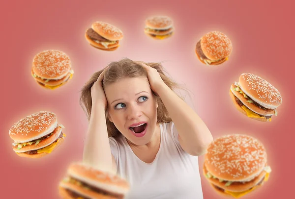 Diet concept. young woman is under stress, burgers are flying ar — Stok fotoğraf