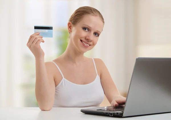 Beautiful girl with a laptop makes a payment online using credit — Zdjęcie stockowe