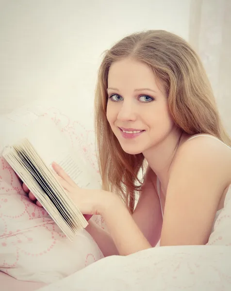 Genç güzel sarışın kadın yatakta yatan ise kitap okuma — Stok fotoğraf