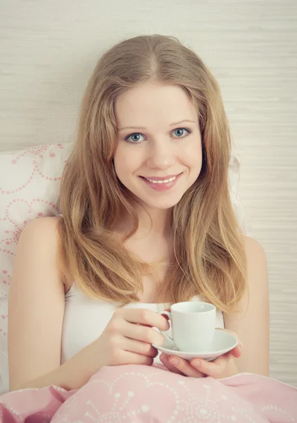 Beautiful young woman with cup of morning coffee in bed — Stock Photo, Image