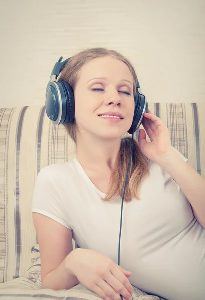 Vacker ung kvinna som lyssnar på musik i hörlurar medan ligg — Stockfoto