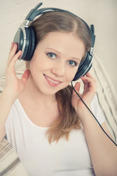 Beautiful young woman enjoys listening to music on headphones on — Stock Photo, Image