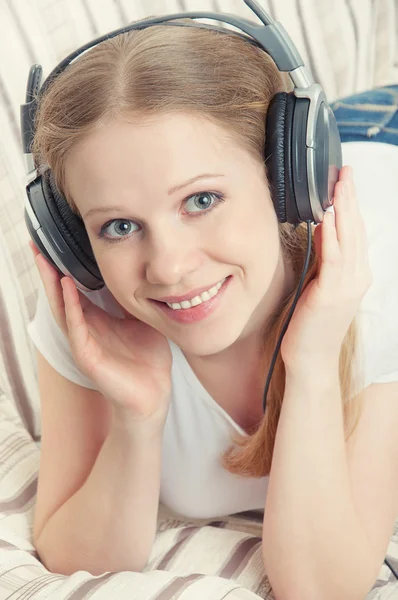 Bella ragazza sorridente gode di ascoltare musica sulle cuffie o — Foto Stock