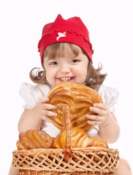 A beautiful little baby in a cap eating a loaf of bread — Stock Photo, Image