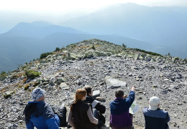 Turystów siedzi na szczycie góry. — Zdjęcie stockowe