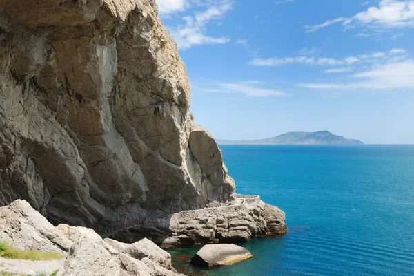 Barlang, a lábánál a hegy a nyugodt tenger. — Stock Fotó