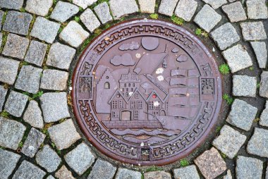 Sewer manhole on stone pavement of Trondheim. clipart