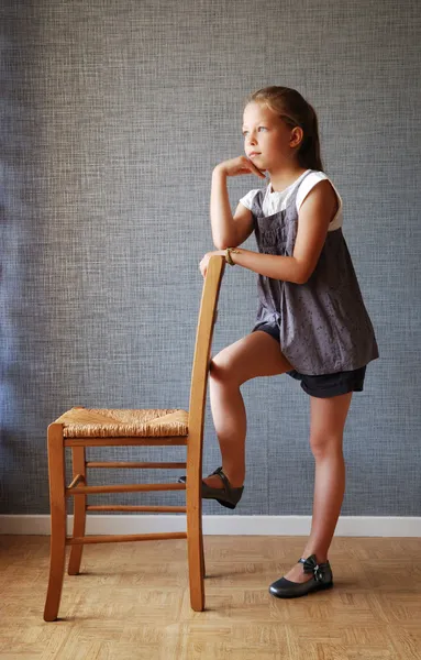Pensive girl near the chair — Stock Photo, Image