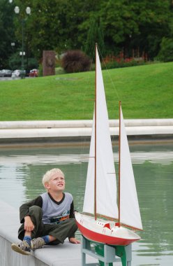 Preteen boy looking at the model yacht. clipart