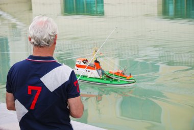 Man controlling a boat model. clipart