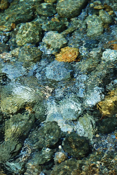 Close-up do leito do rio através de água limpa que flui . — Fotografia de Stock