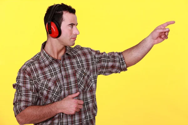 Laborer with headphones on yellow background — Stock Photo, Image
