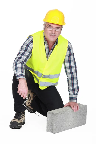 Volwassen metselaar met betonnen blok en troffel — Stockfoto