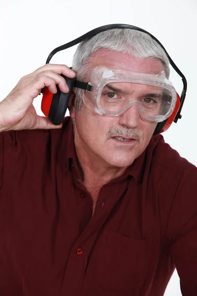 Homem sênior com óculos e fones de ouvido de proteção — Fotografia de Stock
