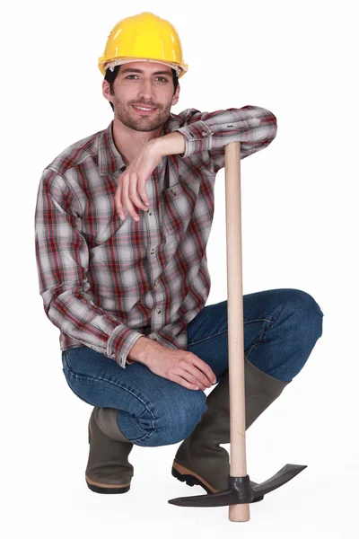 Handsome bricklayer with arm resting on pickaxe — Stock Photo, Image