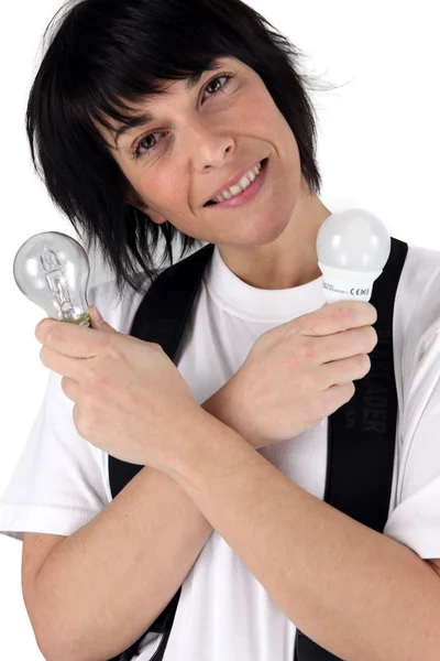 Женщина держит энергосберегающую лампочку — стоковое фото