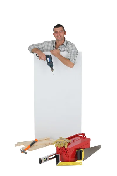 Handyman posando com um sinal em branco e suas ferramentas — Fotografia de Stock