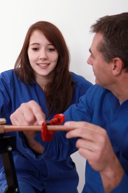 Plumber instructing young female trainee clipart