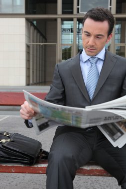 Businessman reading a newspaper clipart