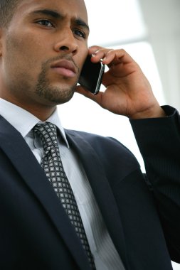 Serious businessman using a cellphone clipart