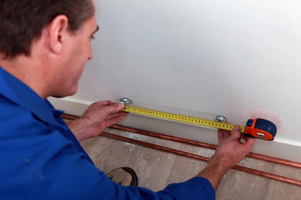 Plumber measuring length of copper pipe — Stock Photo, Image