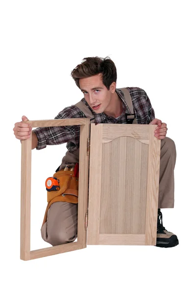 Carpinteiro com uma porta de armário — Fotografia de Stock