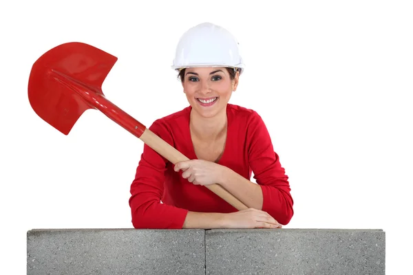 Girl with shovel leaning on a brickwall — Stock Photo, Image