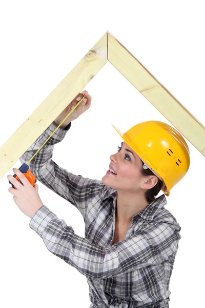 Vrouwelijke timmerman meten houten frame — Stockfoto