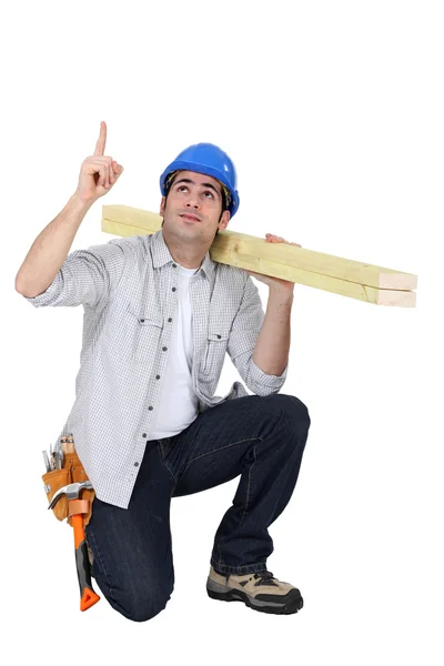 Carpenter kneeling and pointing upwards — Stock Photo, Image